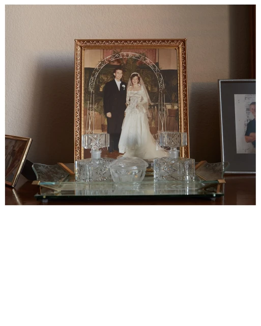 Framed wedding photo with a man and woman in a white dress, displayed on a wooden surface with decorative glass bottles and containers.