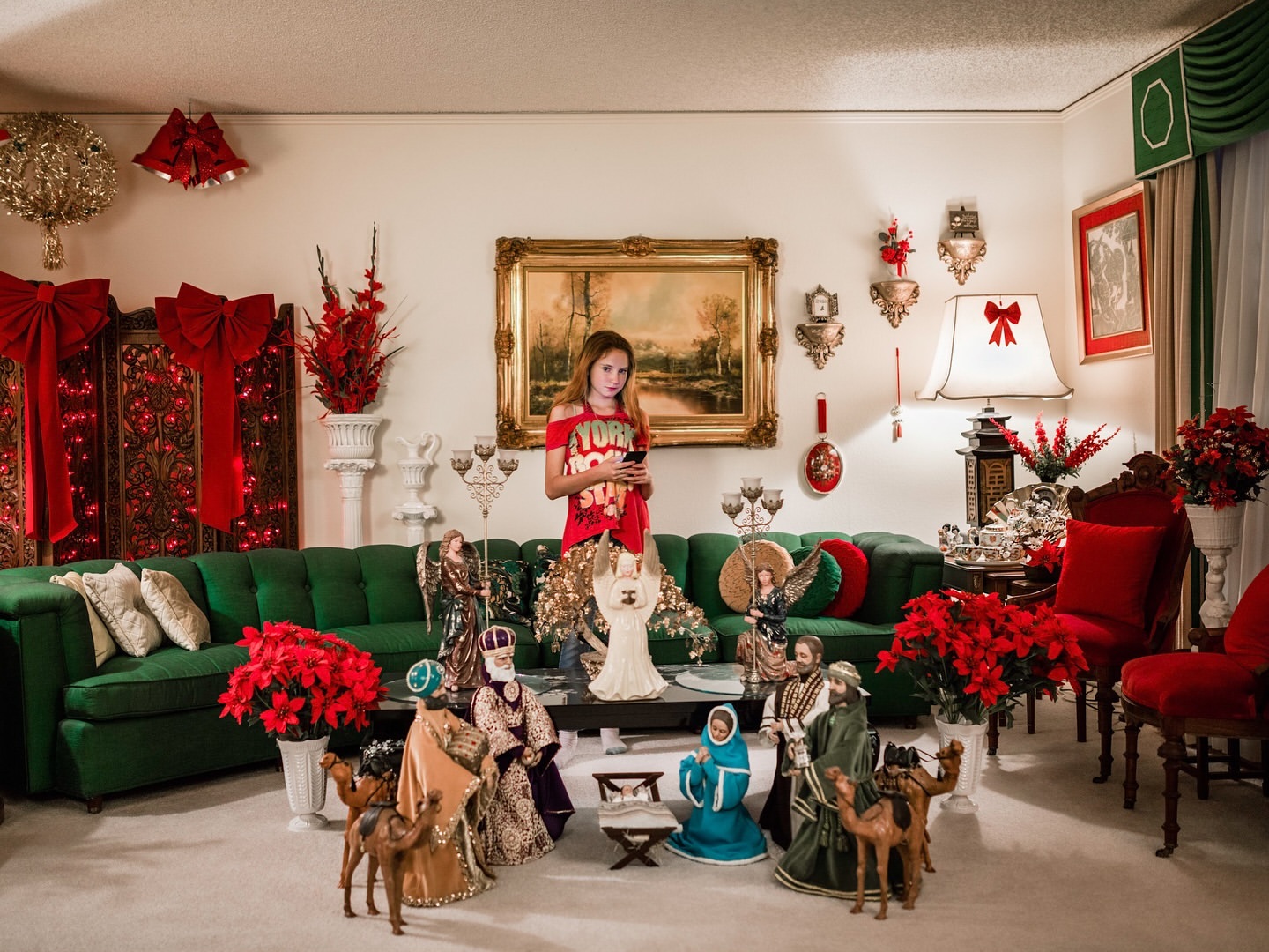 A young woman looks at her phone in a living room heavily decorated with vintage holiday decor, surrounded by Christmas decorations.