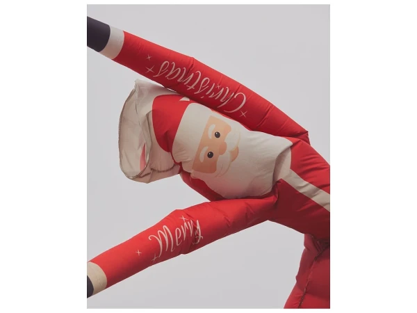Inflatable Santa Claus figure against a neutral sky background, featuring Christmas and Merry text on its red and white design.