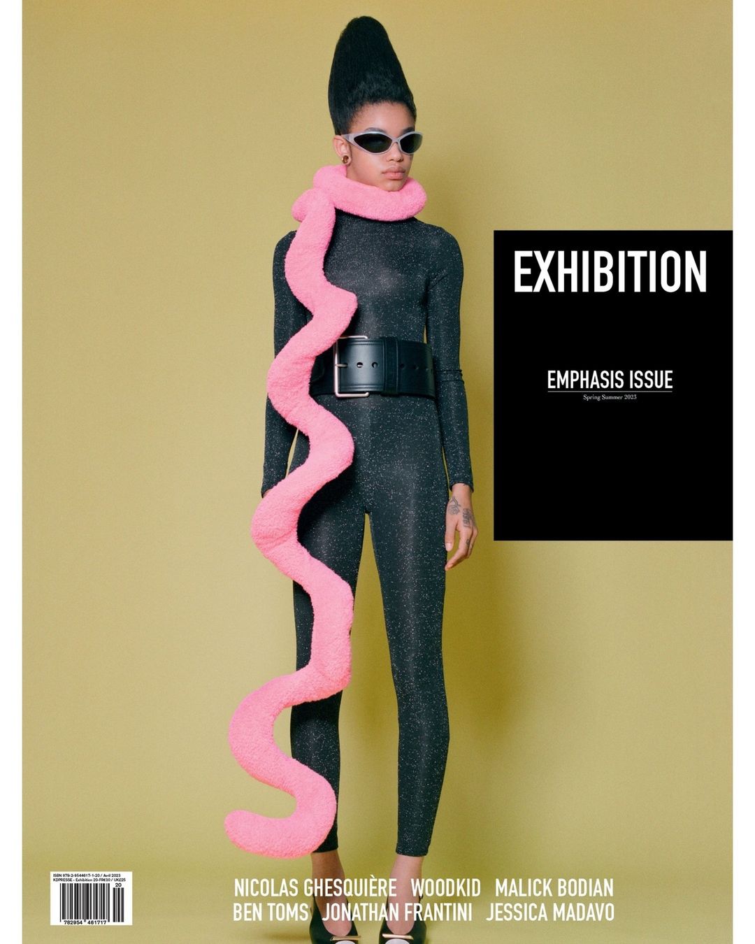 Fashion editorial: Woman in a black bodysuit, sunglasses, and pink scarf stands against a yellow background. Magazine cover on the right.