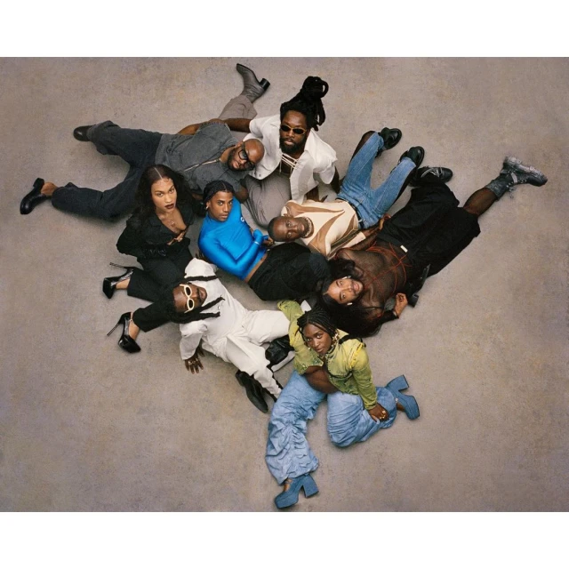 Eye-level shot of nine fashionably dressed adults lying on a seamless gray studio backdrop, featuring diverse attire and poses, shot in studio lighting.