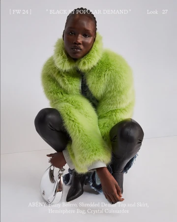 Black woman crouching wearing a fuzzy lime green bolero jacket, shreded denim, and holding a silver handbag against a plain background