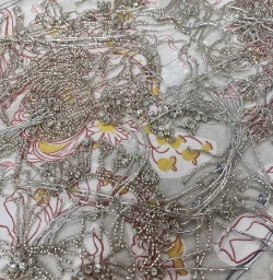 Close-up of intricate silver beadwork and sequined embroidery on patterned fabric by Jessica May Underwood