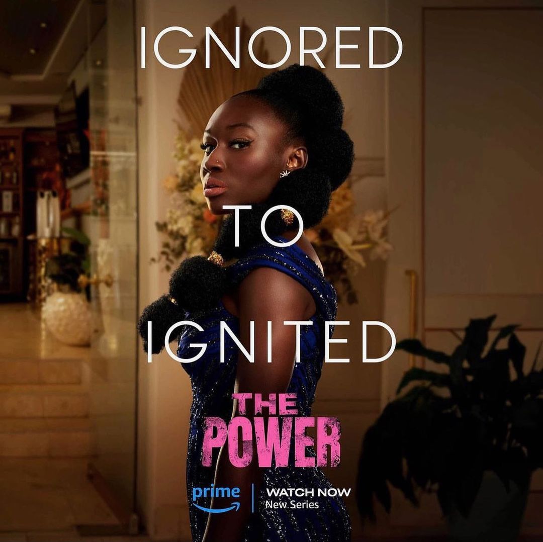Glamorous adult woman with dark hair in elegant blue dress gazes to the side in an indoor setting, with the title, 'The Power' overlaid.