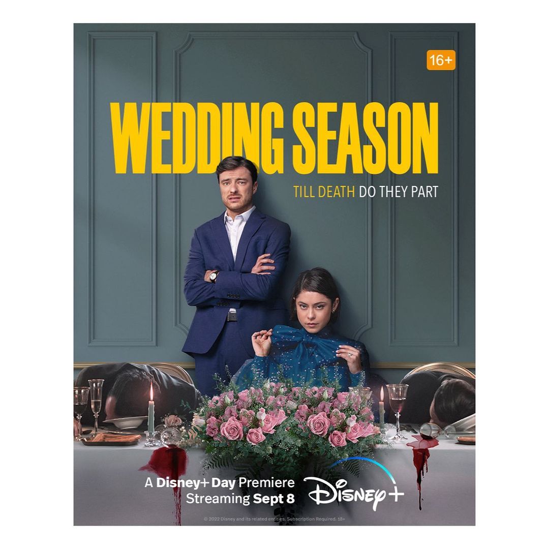 Promotional image for 'Wedding Season' on Disney+ with two actors in formalwear seated at a formal table with flower arrangement.