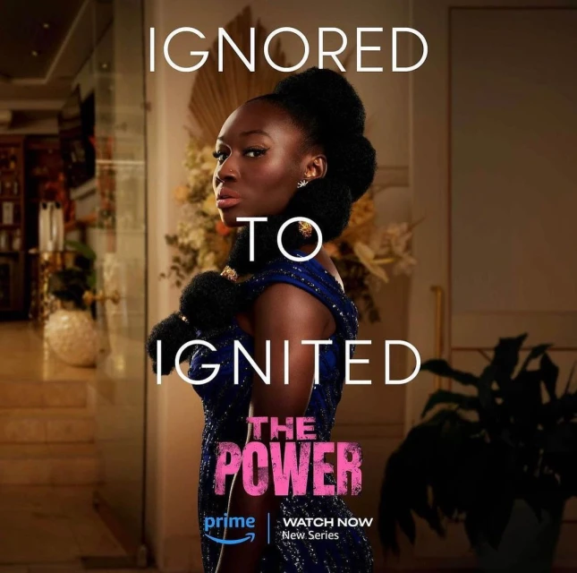 A promotional image for 'The Power' featuring a woman in a blue dress with dark hair, text overlays, and a blurry interior background.