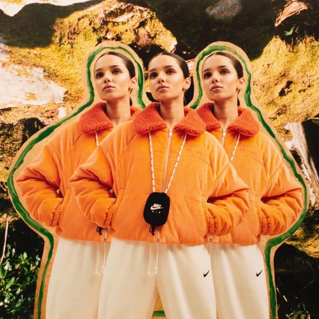 Three women in orange jackets and white sweatpants stand against a collage background featuring natural scenery and cut-out design elements.