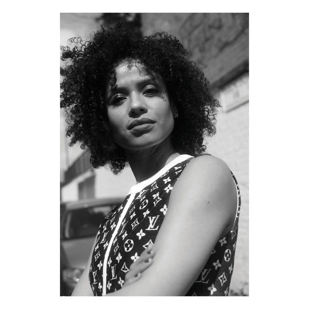 Monochrome portrait of a woman with curly hair wearing a patterned sleeveless top outdoors in London, photographed by Jessie Craig.