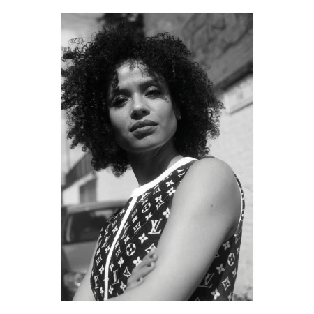 Monochrome portrait of a woman with curly hair wearing a patterned sleeveless top outdoors in London, photographed by Jessie Craig.