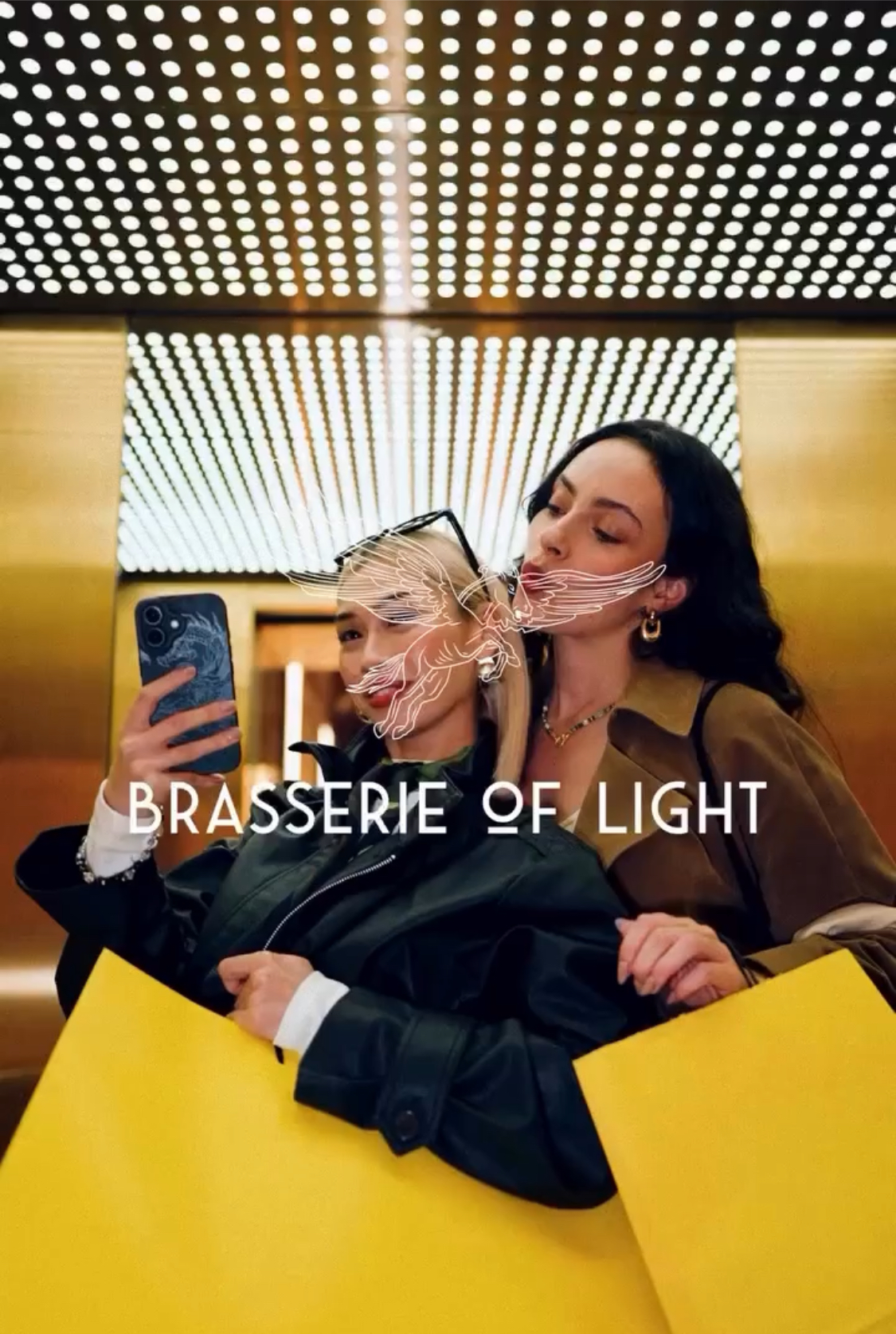 Two women take a selfie with shopping bags in front of an illuminated grid ceiling in an indoor setting with graphic overlays.
