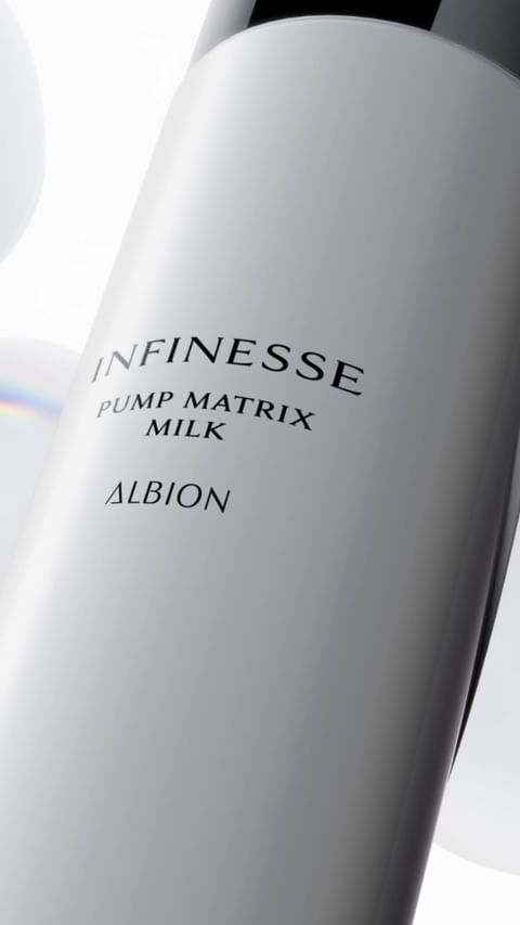 Cosmetic bottle of Infinesse Pump Matrix Milk by Albion. White bottle with black text and cap in a soft, neutral studio setting.