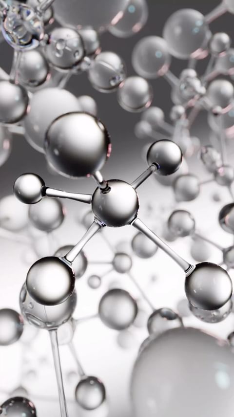 Abstract molecular structure with silver and transparent spheres connected by rods on a blurred gray background.