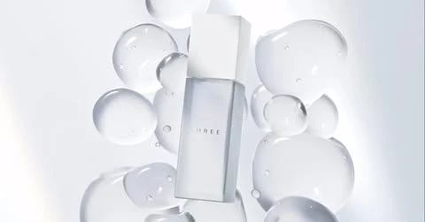 White skincare bottle with a white label and cap. The bottle is surrounded by translucent bubbles on a soft white background.
