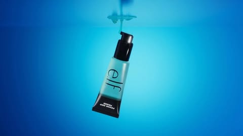 Suspended in blue, e.l.f. Power Grip Primer tube with pump, showcasing brand and product, with water droplets on the container.