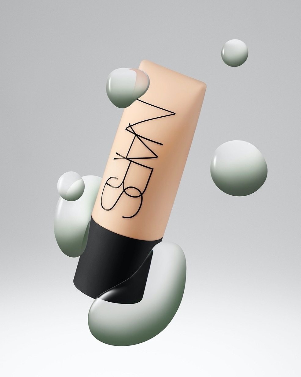 NARS foundation tube with surrounding glossy sphere shapes, showcasing modern beauty product presentation, floating on a soft grey background.