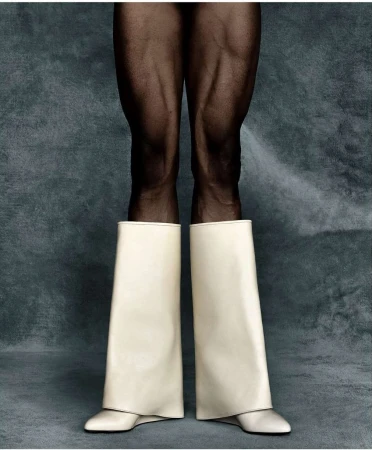 Legs with black tights and wide white boots against a muted grey-blue backdrop, studio lighting with neutral tones, clean fashion shot.