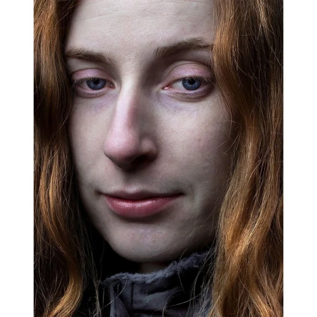 Close-up portrait of a woman with long red hair and blue eyes wearing a dark jacket in London by Jet Swan.