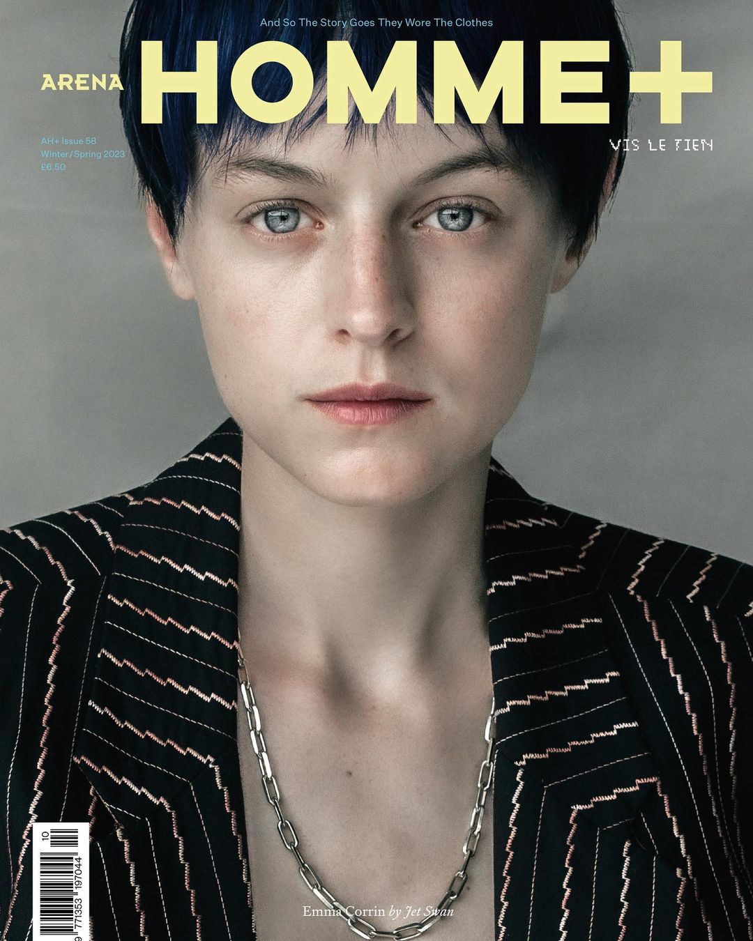 Close-up portrait of Emma Corrin on the cover of Arena Homme+ magazine, wearing a black and white striped blazer and silver chain necklace.