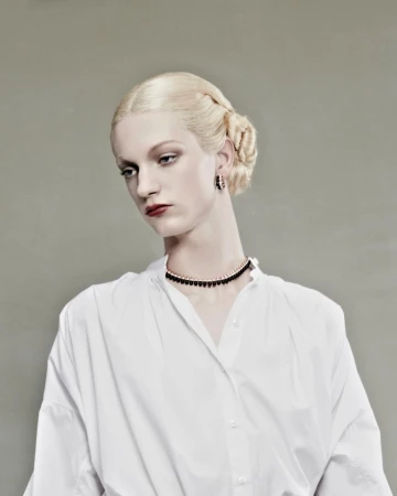 Model with platinum blonde braided hair in a white shirt and dark choker necklace against a grey backdrop by Jet Swan.