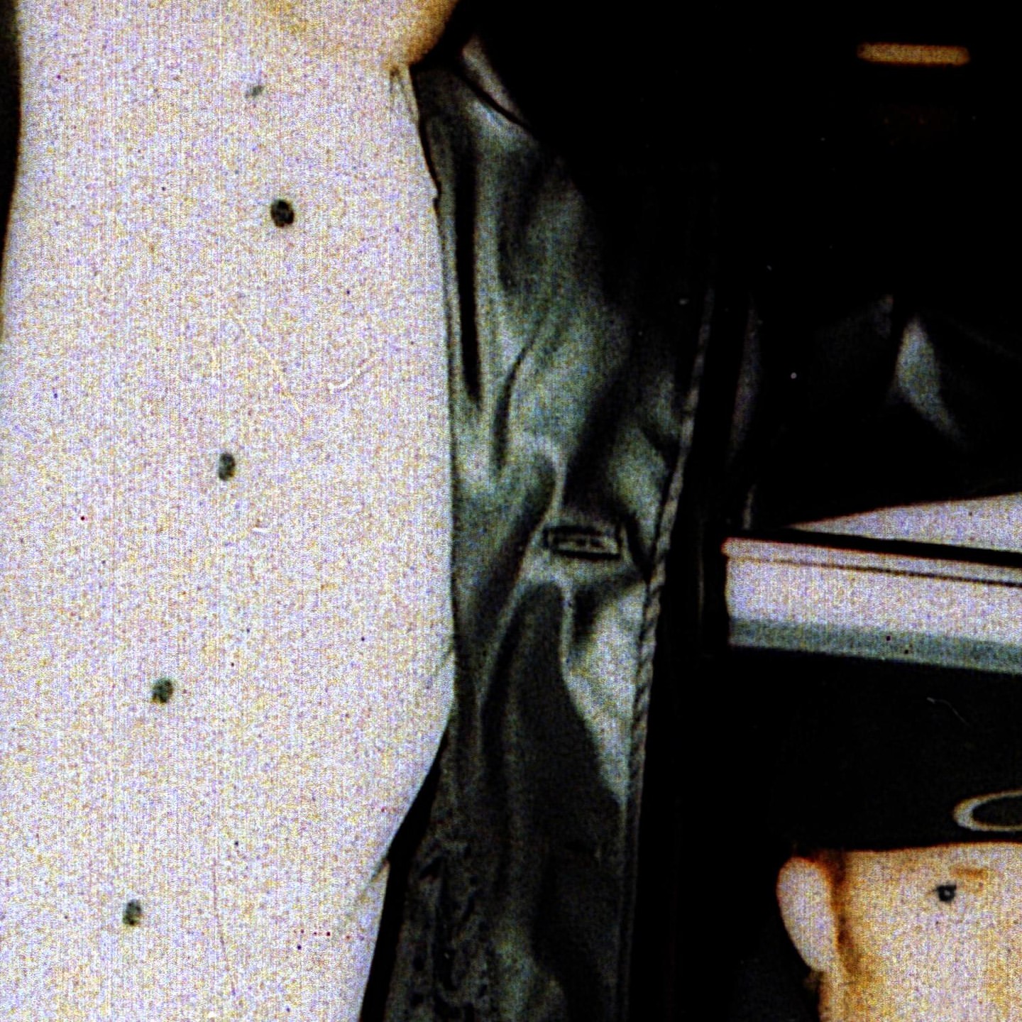 Close-up showcases a light-colored textured jacket with dark buttons, paired with a shiny black leather jacket, set against a dark backdrop.