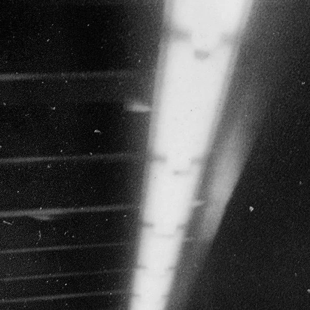 High-contrast black and white image featuring light passing through a set of horizontal grates, casting linear shadows.