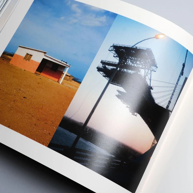Two photographs in a book show a small building with an orange accent and a bridge structure against a blue sky.