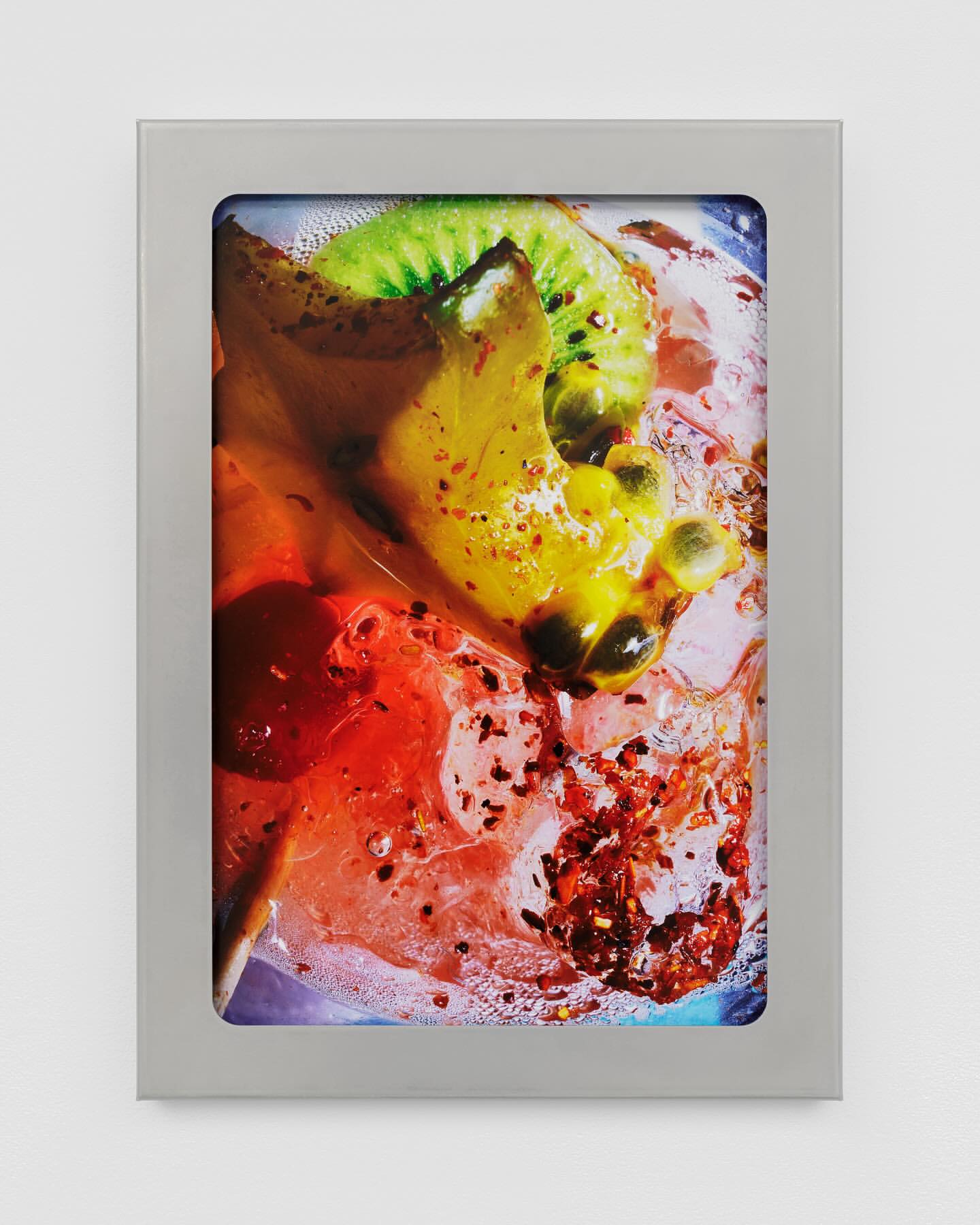Framed still life photo of kiwi, passion fruit, and mango in a clear liquid. Close-up shot highlighting vibrant colors and fruit textures.