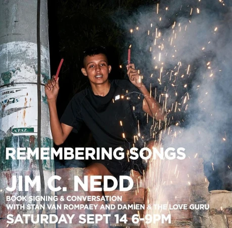 Person holding sparklers at night next to a brick structure with event text promoting Jim C. Nedd and their book 'Remembering Songs'.
