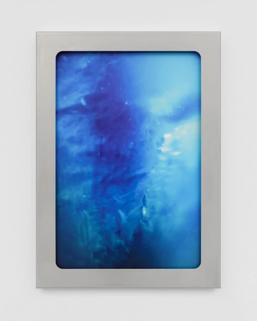Abstract artwork in a metallic frame features a swirling mix of deep blues and whites resembling an underwater scene or cloudy sky.