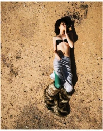 Overhead portrait of a model lying on sandy terrain wearing a black top and light skirt, photographed by Jim C. Nedd.
