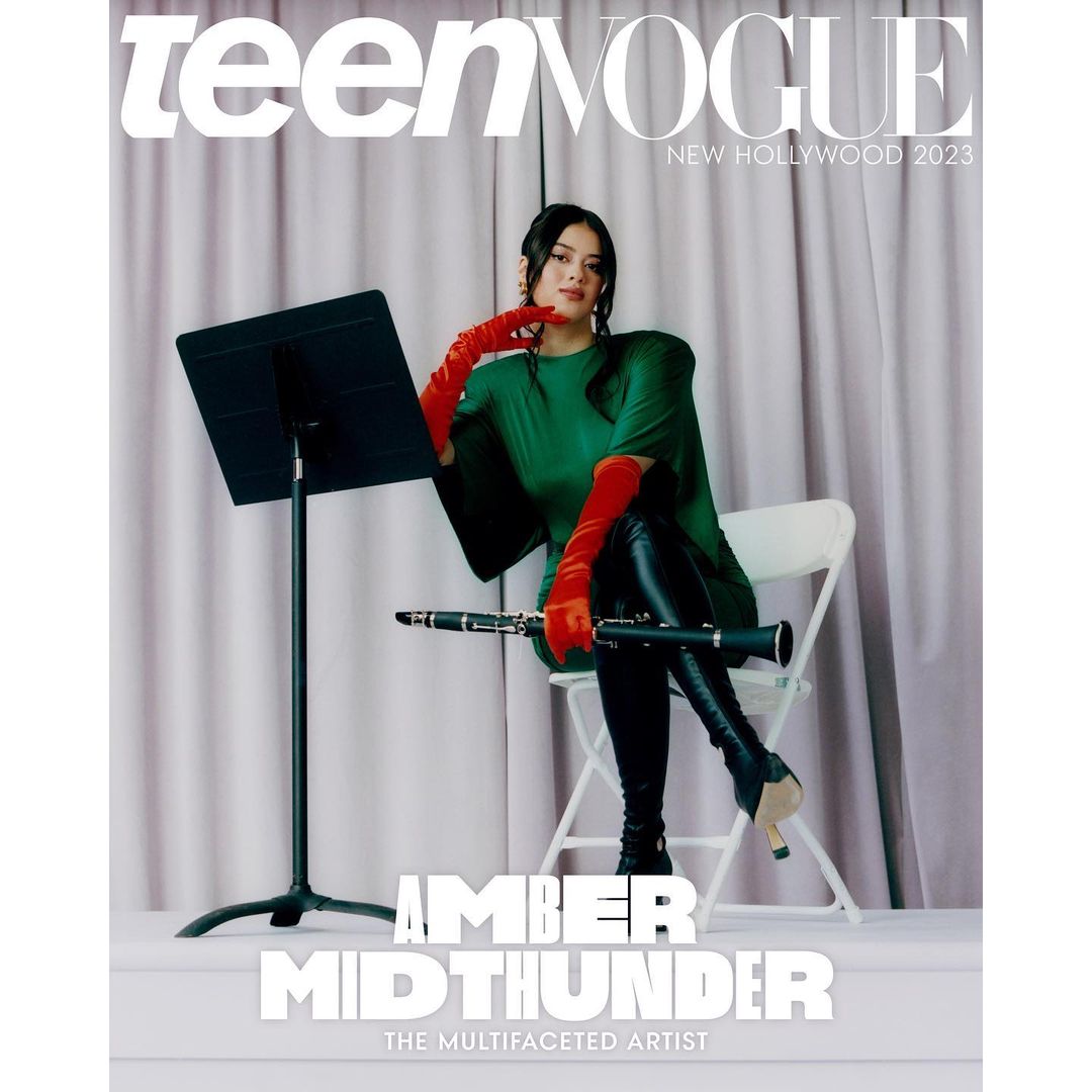 Amber Midthunder poses on a chair, holding a clarinet on the cover of Teen Vogue's New Hollywood 2023 issue, against a curtain backdrop.