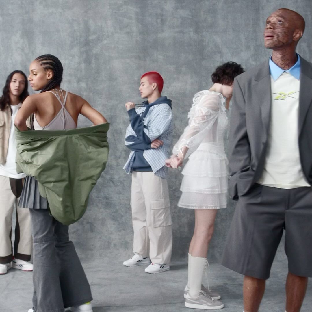 Group of diverse young adult models wearing casual contemporary clothing in a studio setting, posing against a muted gray background.