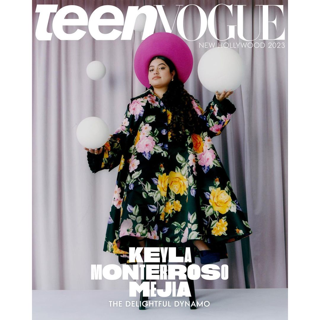 Magazine cover featuring Keyla Monterroso Mejia in a floral coat and hat, holding white spherical objects on a purple backdrop.