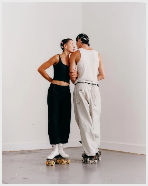 Indoor shot of a couple in casual clothing, standing on roller skates. The woman is leaning in with her eyes closed.