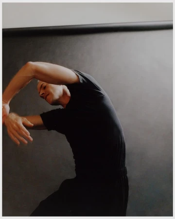 Man wearing a black t-shirt posing with arms curved in a studio by Jingyu Lin