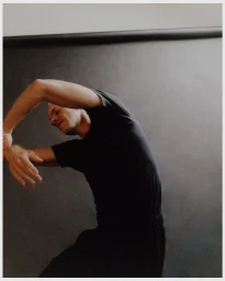 Man wearing a black t-shirt posing with arms curved in a studio by Jingyu Lin