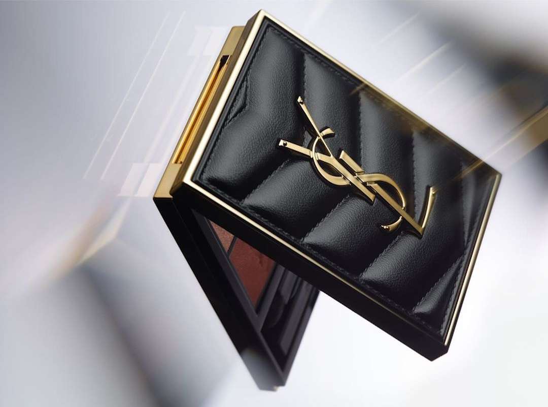 YSL eyeshadow palette compact with a gold logo on a quilted black case, displayed on a glossy surface, beauty product promotion.