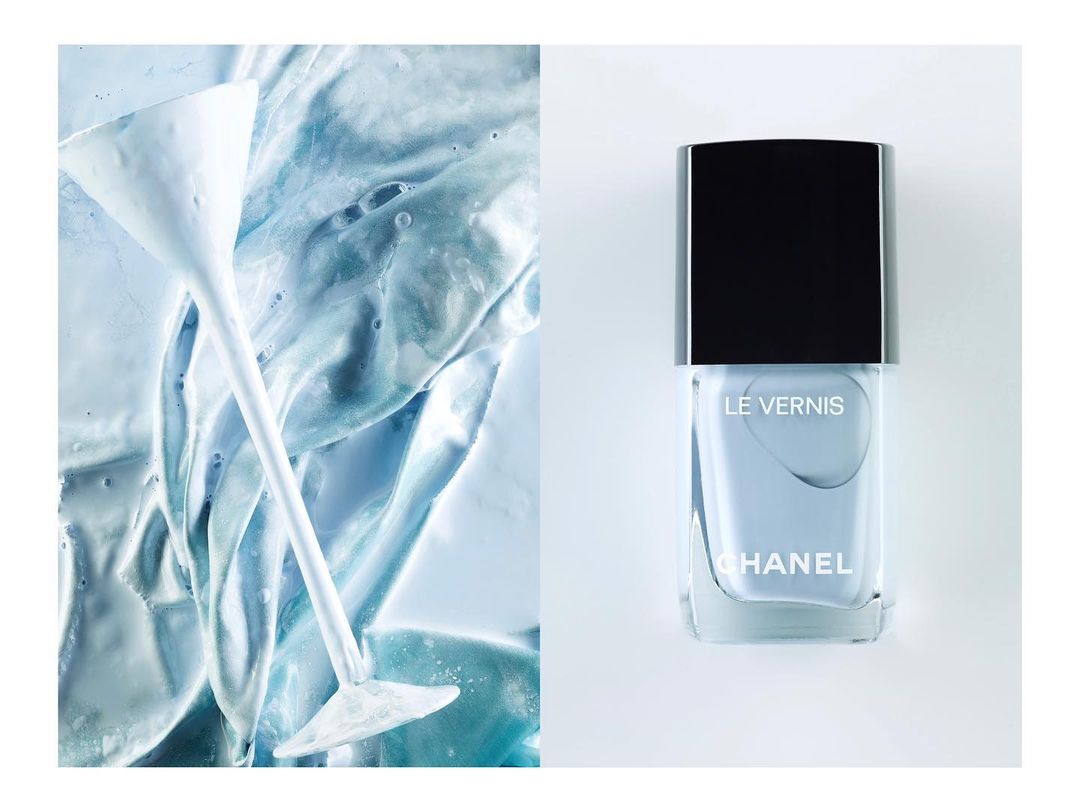 Minimalist product shot of Chanel nail polish in a pale blue hue next to a martini glass filled with matching light blue paint.