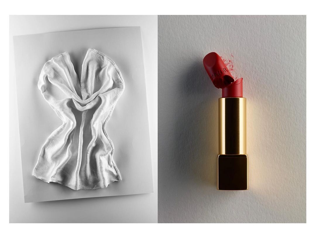 Studio product shot featuring a lipstick tube with a broken tip and a folded white towel on a white background, showcasing textures and form.