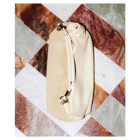 Beige leather bucket bag with a handle, displayed on a patterned marble tile surface, emphasizing luxury fashion and neutral tones.