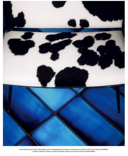 Close-up of chair with black and white cowhide pattern on seat and back, metal legs, blue quilted tile floor visible.