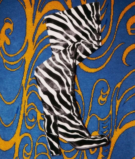 Striking zebra-striped high-heeled boot stands out on a blue and gold ornate patterned background, a fusion of fashion and art.