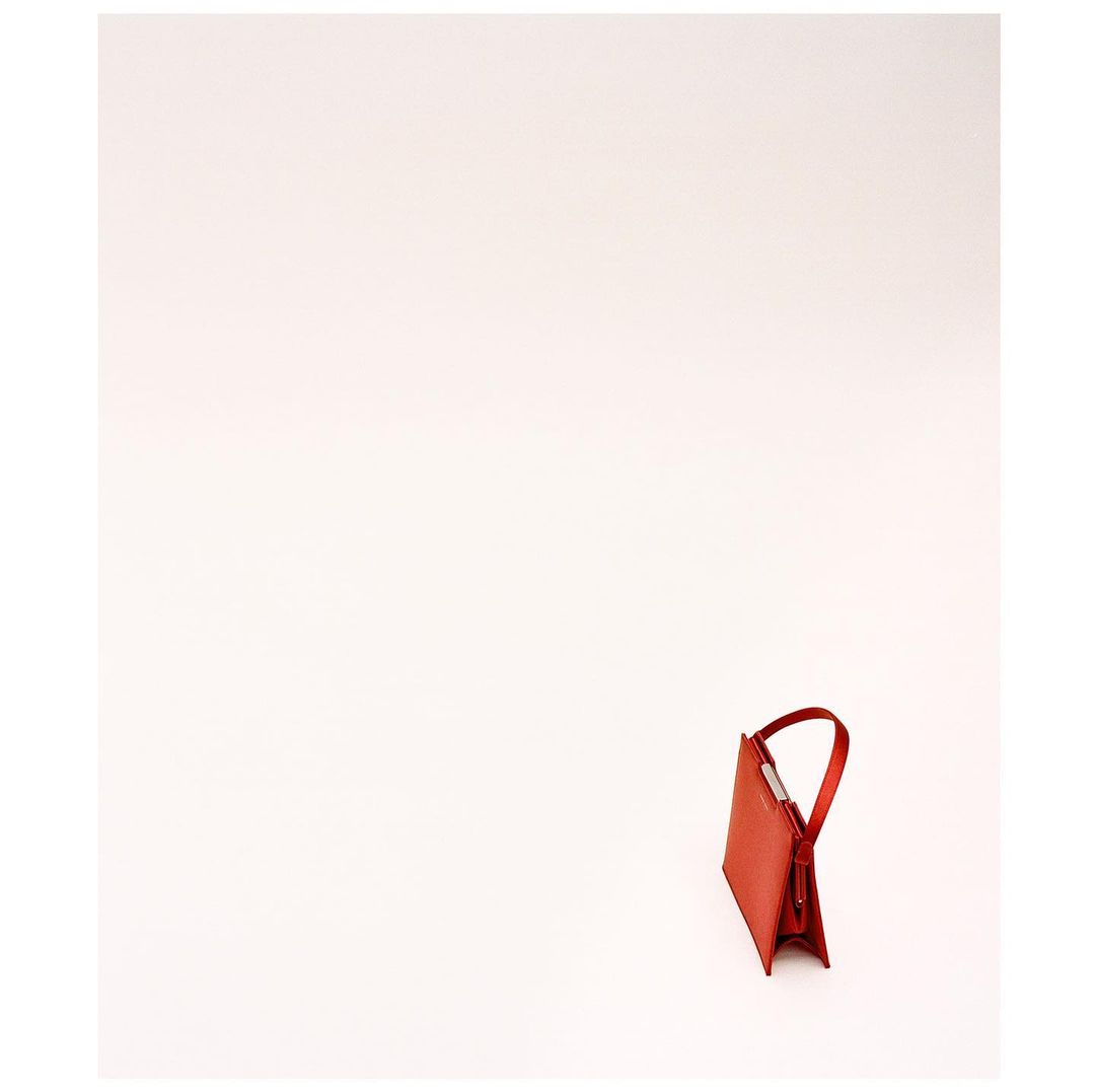 Close-up studio shot of a red leather purse on a white background. The minimalistic composition is evenly lit and focuses on fashion.