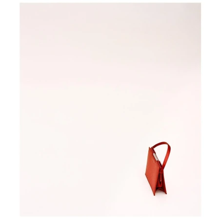 A structured red leather handbag with a curved handle resting on a plain white studio background.