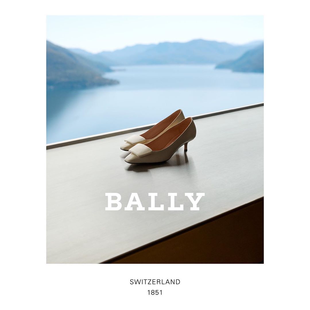 Elegant cream-colored heels are displayed against a stunning lake and mountain backdrop, highlighting the brand BALLY and Switzerland.