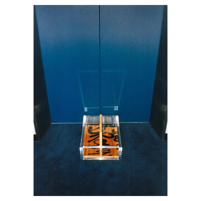 Elevated angle on a clear acrylic box on a navy blue textured surface against a blue and black panel background. 