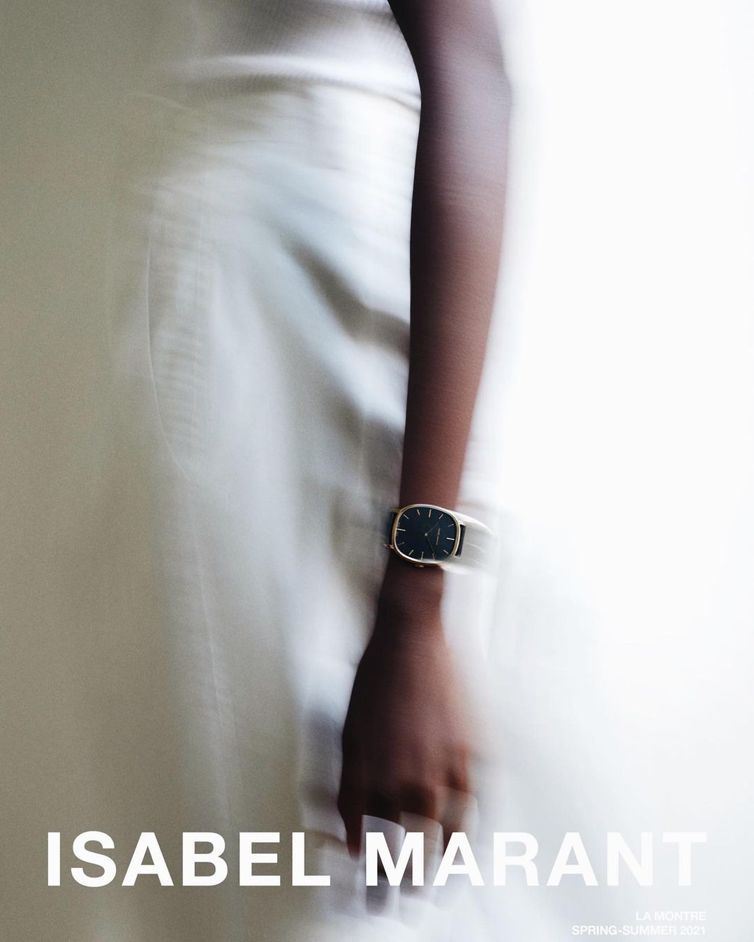 Close-up of a person wearing a wristwatch with a dark face on a light background with subtle motion blur.