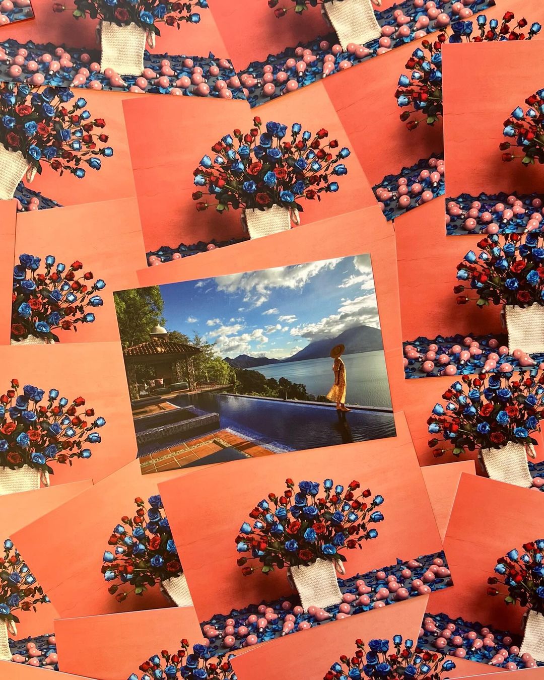 Many postcards show a woman by a pool overlooking a lake, with bouquets of red, white, and blue roses scattered around.