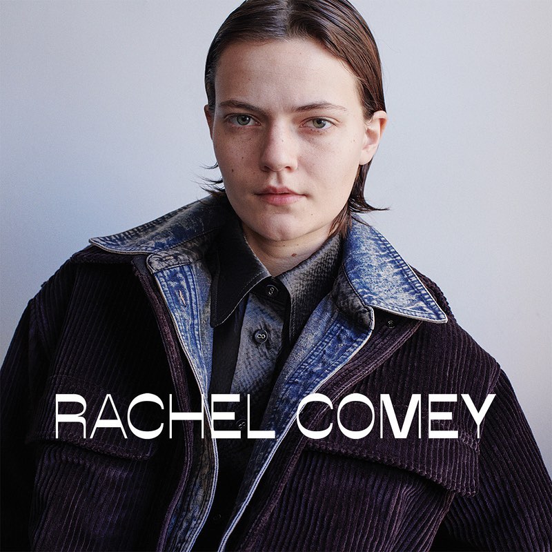 Portrait of a fair-skinned woman with short brown hair wearing a denim collared jacket over a button-down shirt in a studio.