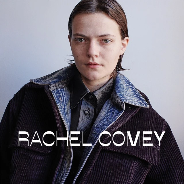 Portrait of a fair-skinned woman with short brown hair wearing a denim collared jacket over a button-down shirt in a studio.